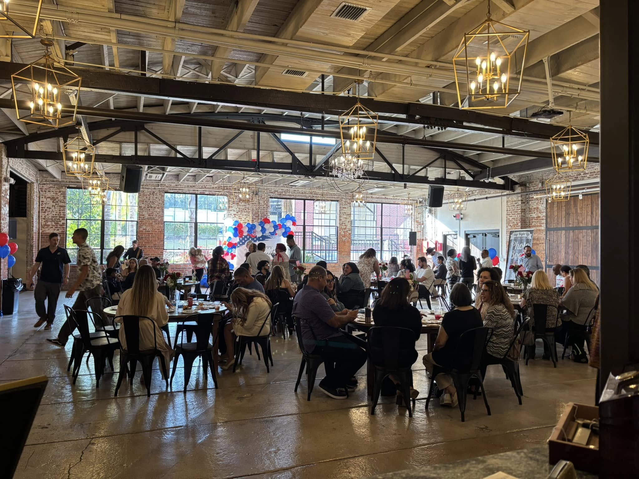 Full event hall with guests at tables and bar service