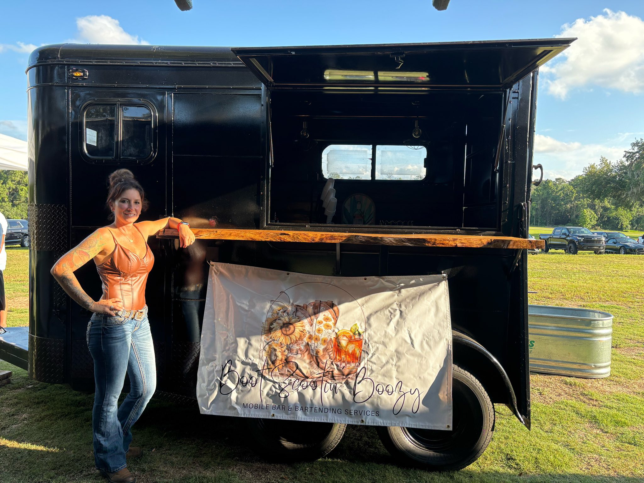 Kristin standing proudly beside the Boot Scootin' Boozy horse trailer
